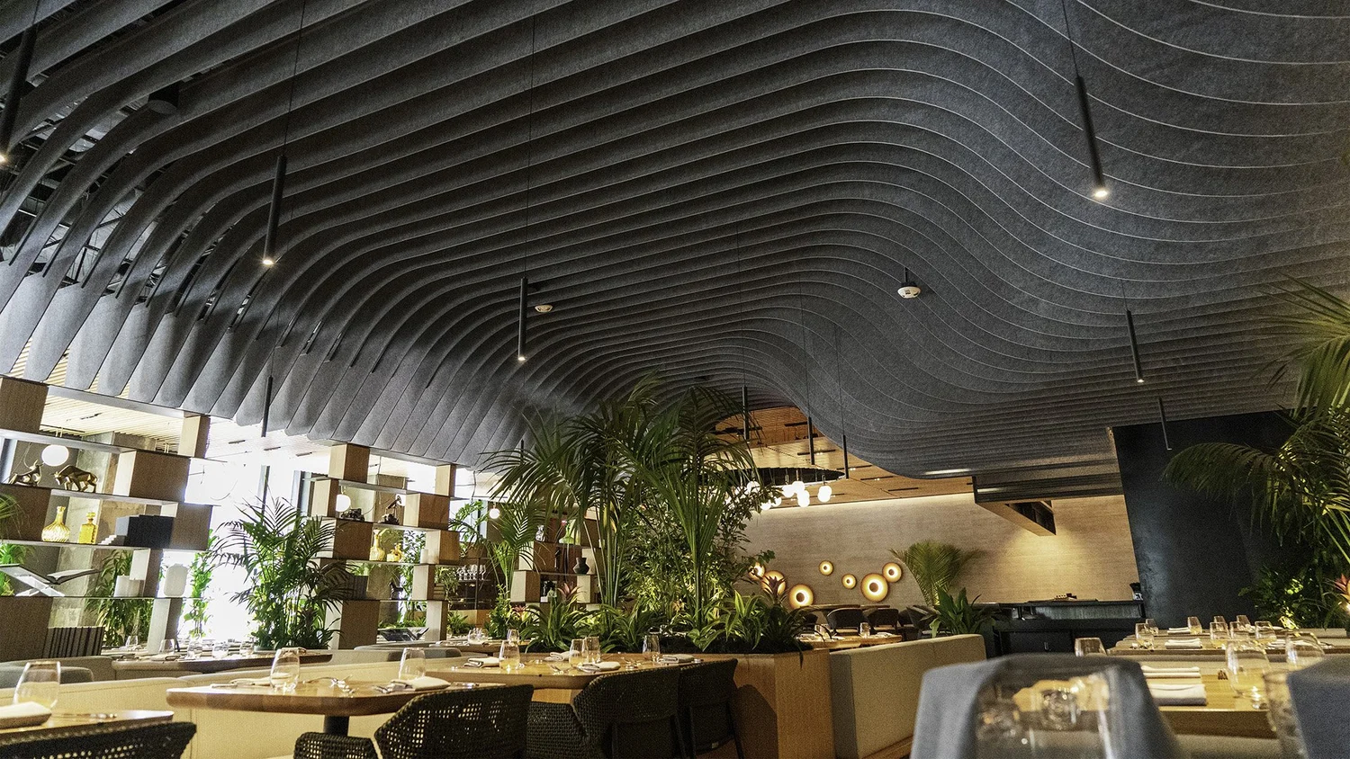 Layered acoustic ceiling installation with curved dark baffles.